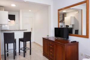 a living room with a television on a dresser with a mirror at APARTAMENTOS PALASIET in Benidorm