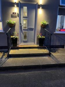 a blue door with two potted plants on the steps at Alexandra Hotel in Blackpool