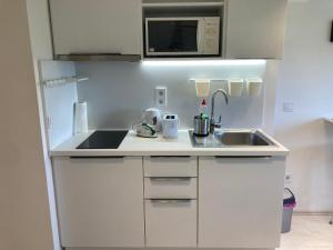a white kitchen with a sink and a microwave at Roland Apartment - PUSKAS in Budapest