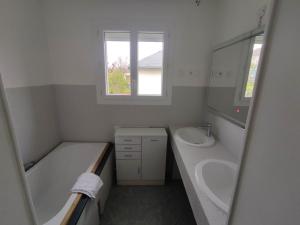 W łazience znajduje się wanna, umywalka i lustro. w obiekcie Petite maison de 70m2 très calme w mieście Bellerive-sur-Allier