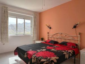 una camera da letto con un grande letto con fiori rossi di Villa Los Faramondos Naturehouse a Turre