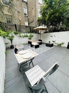 um pátio com mesas e cadeiras e um guarda-sol em Londwell, Luxe and Leaves, Chelsea Flat with Private Garden em Londres