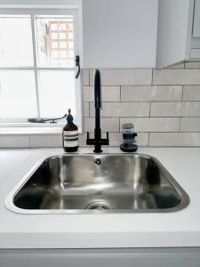 a stainless steel sink in a kitchen with a window at Londwell, Luxe and Leaves, Chelsea Flat with Private Garden in London