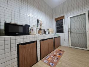 a kitchen with white tiled walls and a counter with a tv at KANA Homehug in Ban Nong Hin