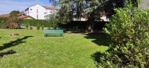 un banco verde sentado en el césped en un patio en Studio au calme, en Péronnas