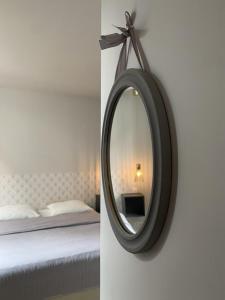 un espejo colgado en una pared junto a una cama en Hysope : Studio aux couleurs toutes douces !, en Bagnères-de-Bigorre