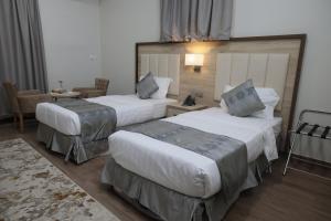 Cette chambre comprend 2 lits et une table. dans l'établissement فندق روز الجنوب, à Abū Ḩajar al A‘lá