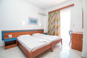 a bedroom with a bed and a desk and a window at Ano Kampos Hotel & Suites in Faliraki