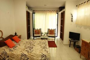 a bedroom with a bed with orange pillows and a television at House at Centro Histórico with pool in Mérida