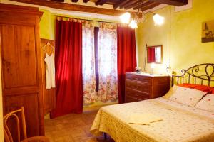 1 dormitorio con 1 cama y una ventana con cortinas rojas en Antica Pietra holiday house with pool, en Montaione