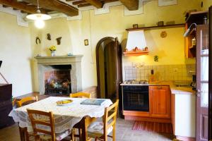 a kitchen with a table and a stove and a fireplace at Antica Pietra holiday house with pool in Montaione