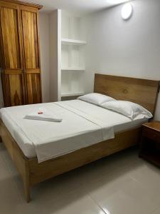 a bedroom with a large bed with a wooden headboard at ApartaHotel Los Naranjos in Apartadó