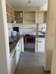 a kitchen with white cabinets and a stove top oven at Departamento moderno y equipado 3-B in Corrientes
