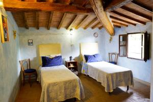 two beds in a room with blue walls and wooden ceilings at Antica Pietra holiday house with pool in Montaione