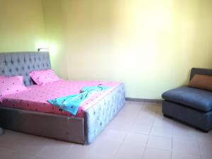 a small bedroom with a bed and a chair at Studio meublé Yaoundé Centre ville in Yaoundé