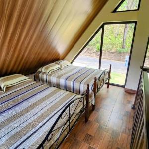 2 camas en una habitación con ventana grande en Cabaña de montaña en Altos del María, en Sorá