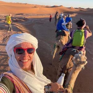 a woman riding a camel in the desert at berber sahara in Zagora