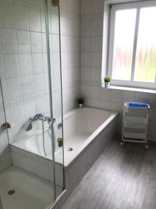 ein weißes Bad mit einer Badewanne und einem Fenster in der Unterkunft Ferienhaus Ankerplatz in Fehmarn