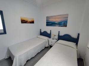 コニル・デ・ラ・フロンテーラにあるFuenteMar -Junto Playa y Centro-Garaje-Familias y parejasの白い壁の客室で、ツインベッド2台が備わります。