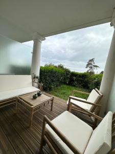 eine Veranda mit 2 Stühlen, einem Sofa und einem Tisch in der Unterkunft Les Maisons de CharlocHomes, F1 Vue Mer in Trouville-sur-Mer