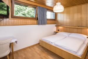 a bedroom with a bed and a desk and windows at Apartments Chalet Zirm in Santa Cristina in Val Gardena