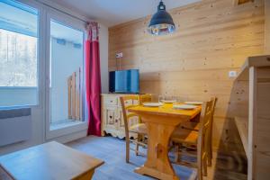 a dining room with a wooden table and chairs at Appartement cosy 1 chambre 4 pers face pistes 09 in LʼHuez