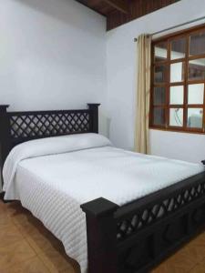 a bedroom with a black bed with a window at Amplia Casa en Paquera in Paquera