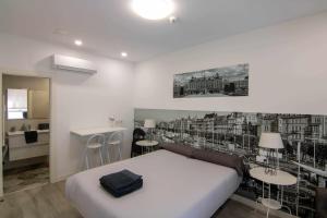 a bedroom with a white bed and a kitchen at Suite estocolmo in León