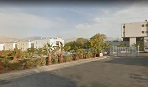 une rue avec une clôture, des arbres et des bâtiments dans l'établissement מאנטה manta דירת נופש באילת, à Eilat