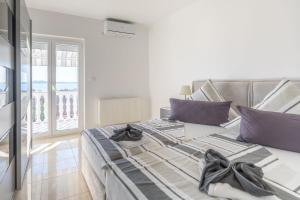 um quarto com uma cama grande e almofadas roxas em Kiki, No 3 em Zadar