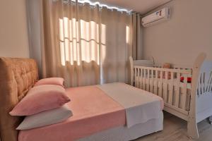 a baby crib with pink pillows and a crib at Residencial London AP 104 in Gramado