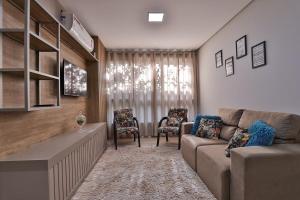 a living room with a couch and two chairs at Residencial London AP 104 in Gramado