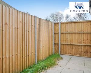 a wooden fence with a sidewalk in front of it at Bright and Stylish One Bedroom Flat by Direct2hosts Short Lets with great location! in London
