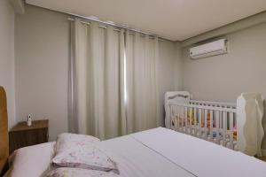 a small bedroom with a crib and a window at Residencial via Florida AP102 D in Gramado