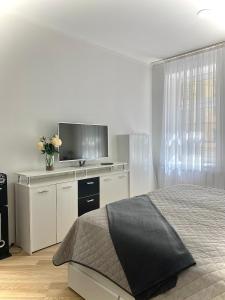 a white bedroom with a bed and a tv at @HOME in Chemnitz