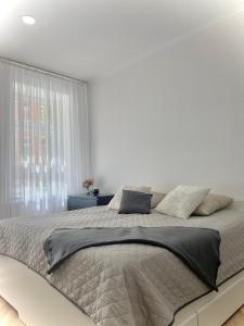 a white bedroom with a large bed with gray sheets at @HOME in Chemnitz