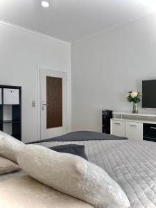 a white bedroom with a bed and a television at @HOME in Chemnitz