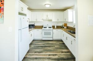 a white kitchen with white appliances and wooden floors at Large Condo Sleeps 10 near Downtown Los Angeles in Los Angeles