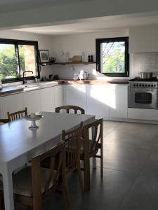 a kitchen with a table and chairs and a kitchen with white cabinets at Le Balcon in Castelvieilh +19 photos
