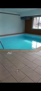 a swimming pool with blue water in a building at Location appartement à Bonascre in Ax-les-Thermes