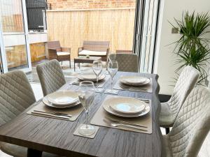 a wooden table with chairs and plates and wine glasses at Luxury Modern Private Villa in Brighton in Brighton & Hove