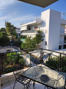 - un balcon avec une table en verre et un bâtiment dans l'établissement Saronida Art Apartment, à Saronida