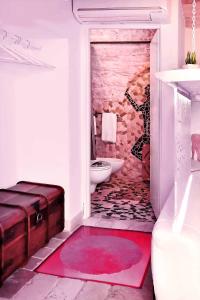 a bathroom with a toilet and a red rug at l'angolo di Gaudì, alcoba Capriccio in Putignano