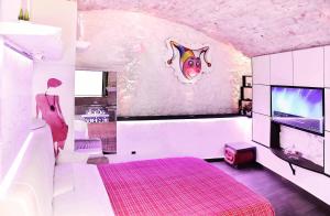 a bedroom with a pink bed and a tv at l'angolo di Gaudì, alcoba Capriccio in Putignano