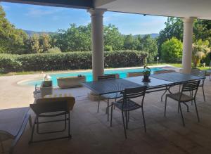 eine Terrasse mit einem Tisch, Stühlen und einem Pool in der Unterkunft Villa Mycènes in Garéoult