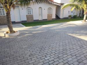 a brick driveway with a palm tree in front of a building at Vista Oceanica Pousada in Marataizes