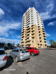 two cars parked in a parking lot in front of a tall building at kato's apartment in Tbilisi City