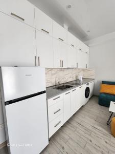 a white kitchen with a sink and a dishwasher at kato's apartment in Tbilisi City