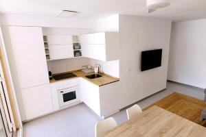 eine Küche mit weißen Schränken, einem Tisch und einem TV in der Unterkunft Precioso apartamento Reformado en 1a linea de mar sin vistas in Calella de Palafrugell