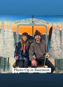 un hombre y una mujer sentados en un carro con esquís en Chair Lift Lodge- Best Location in EVL Village! en Ellicottville
